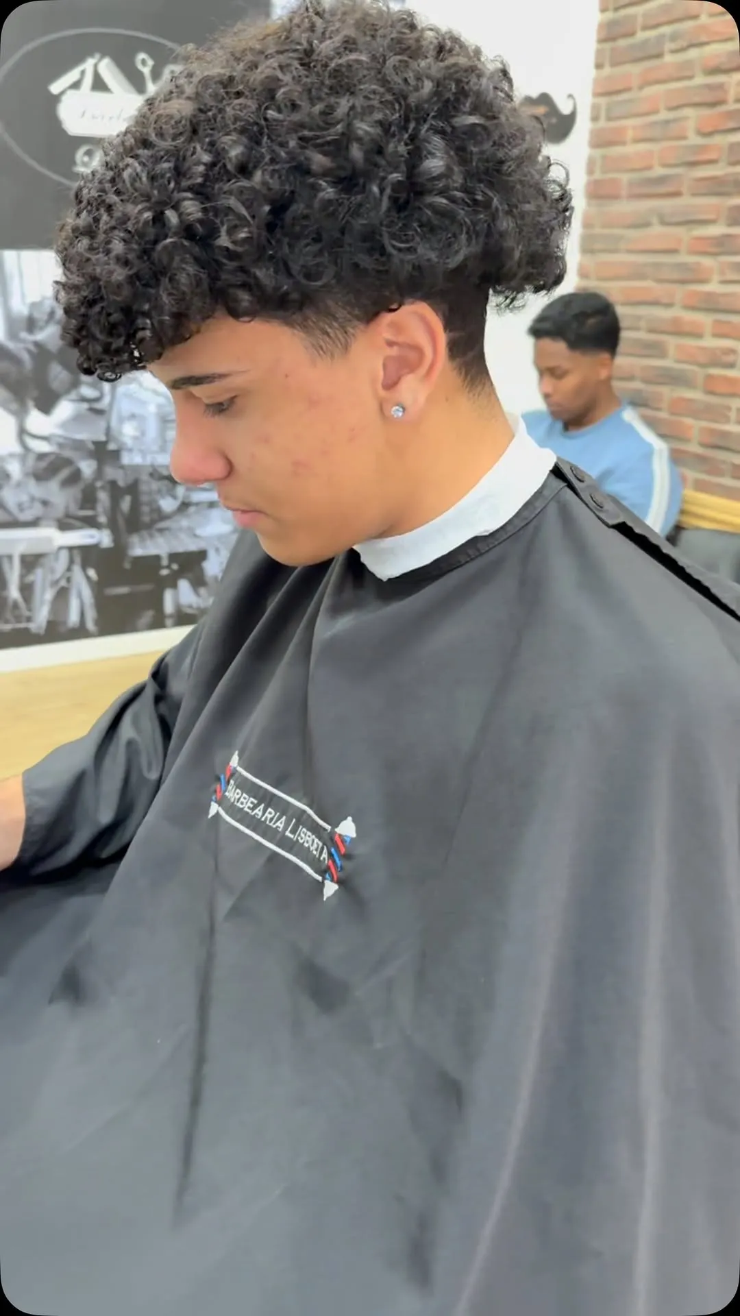 Corte em cabelo encaracolado com a capa da Barbearia Lisboeta